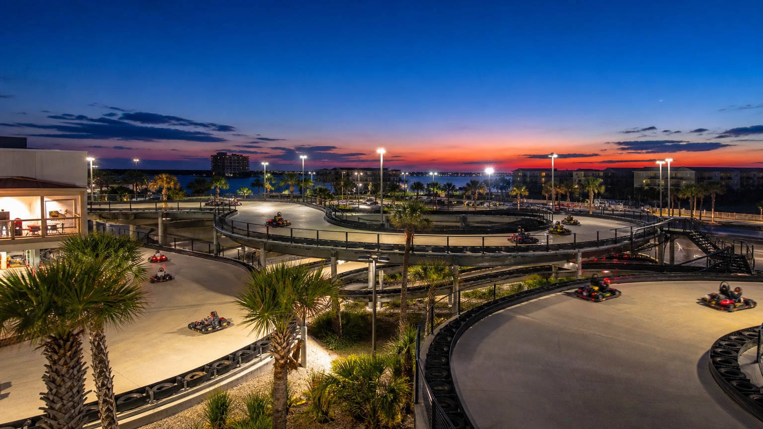 Go-karts racing at night at Track Destin entertainment complex with bright track lighting