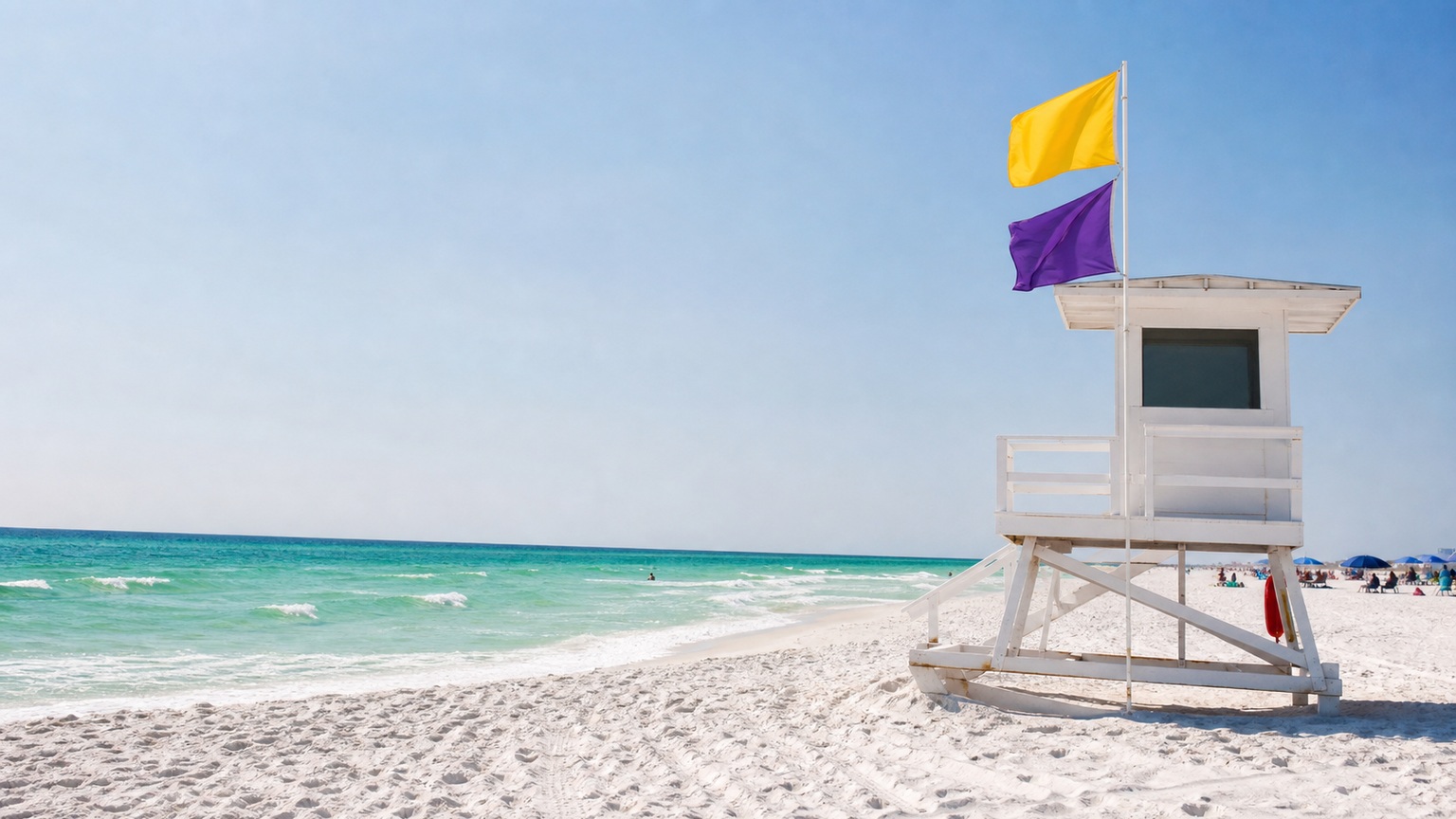 Lifeguard tower on a white sand beach in Destin Florida with colored beach safety flags flying in the Gulf breeze on a sunny summer day