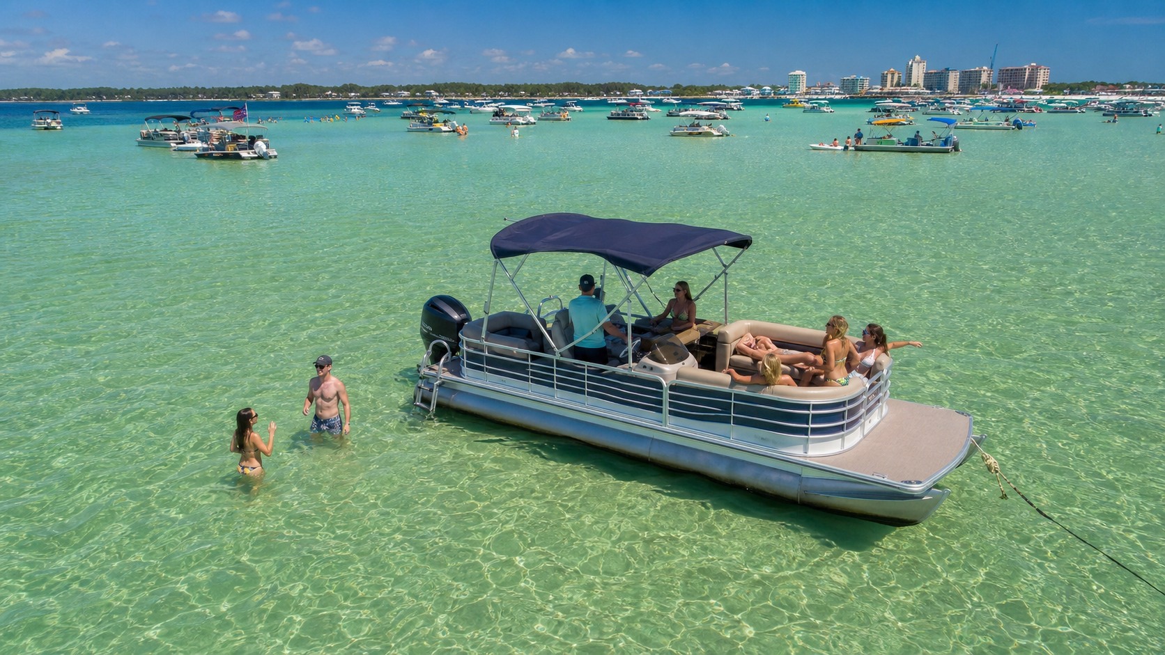 Excited vacationers on a pontoon boat anchored at the shallow Crab Island sandbar in Destin Florida with emerald green water all around them on a bright summer day
