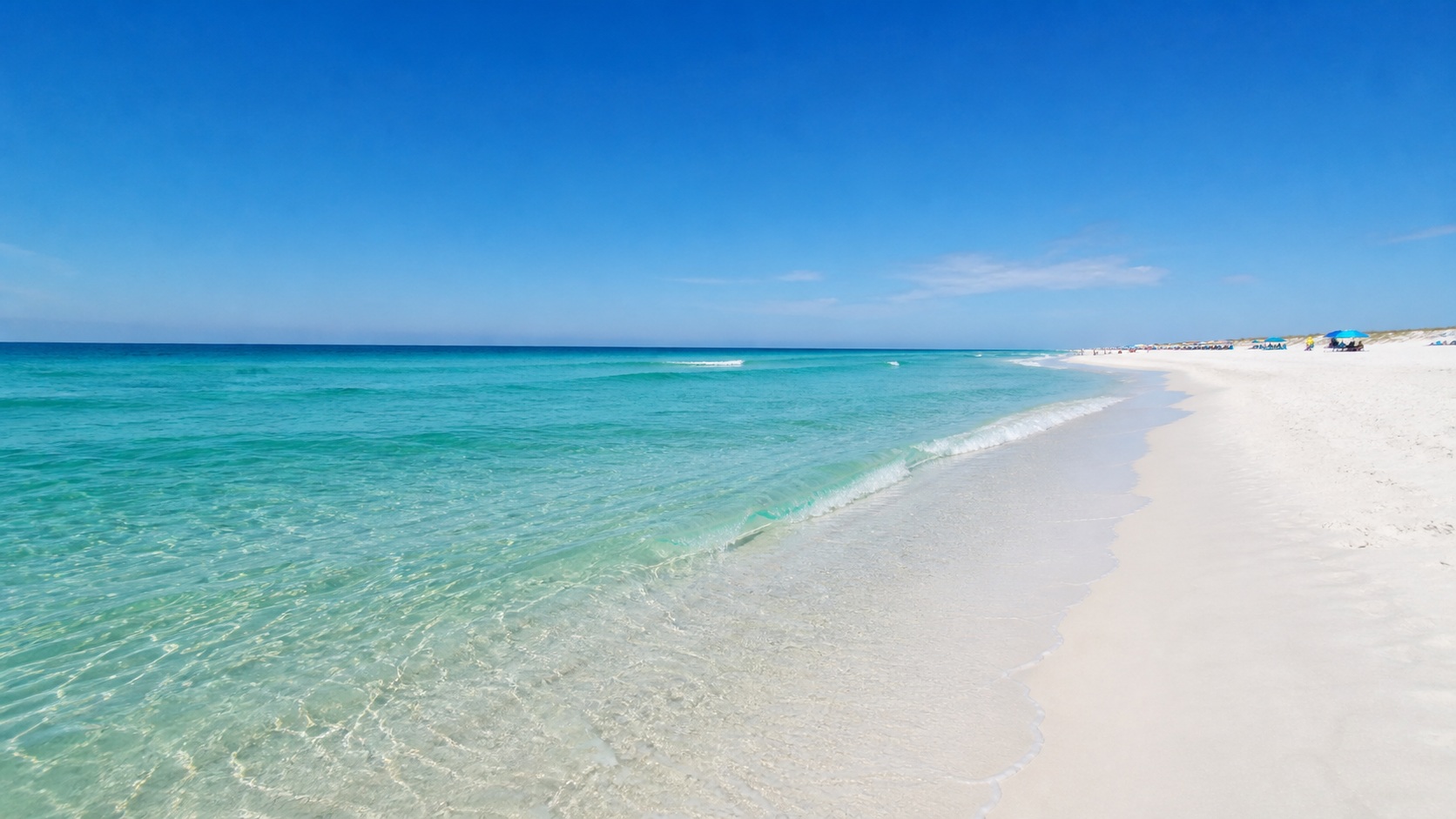 Brilliant white sugar-sand Destin Florida beach with emerald green and turquoise Gulf water in shallow areas and deep emerald beyond, clear sky, summer